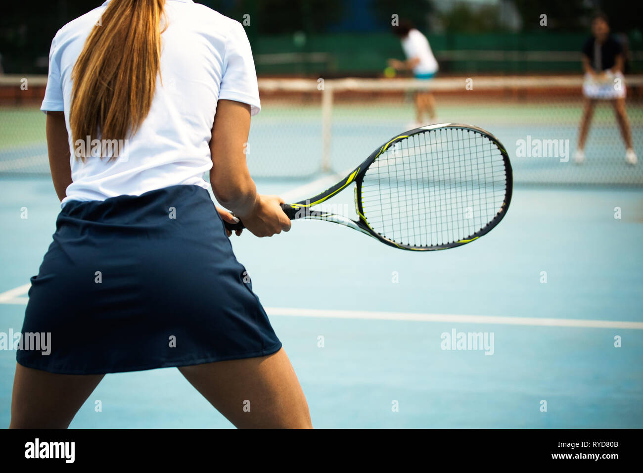 Young happy woman playing tennis at tennis court Stock Photo