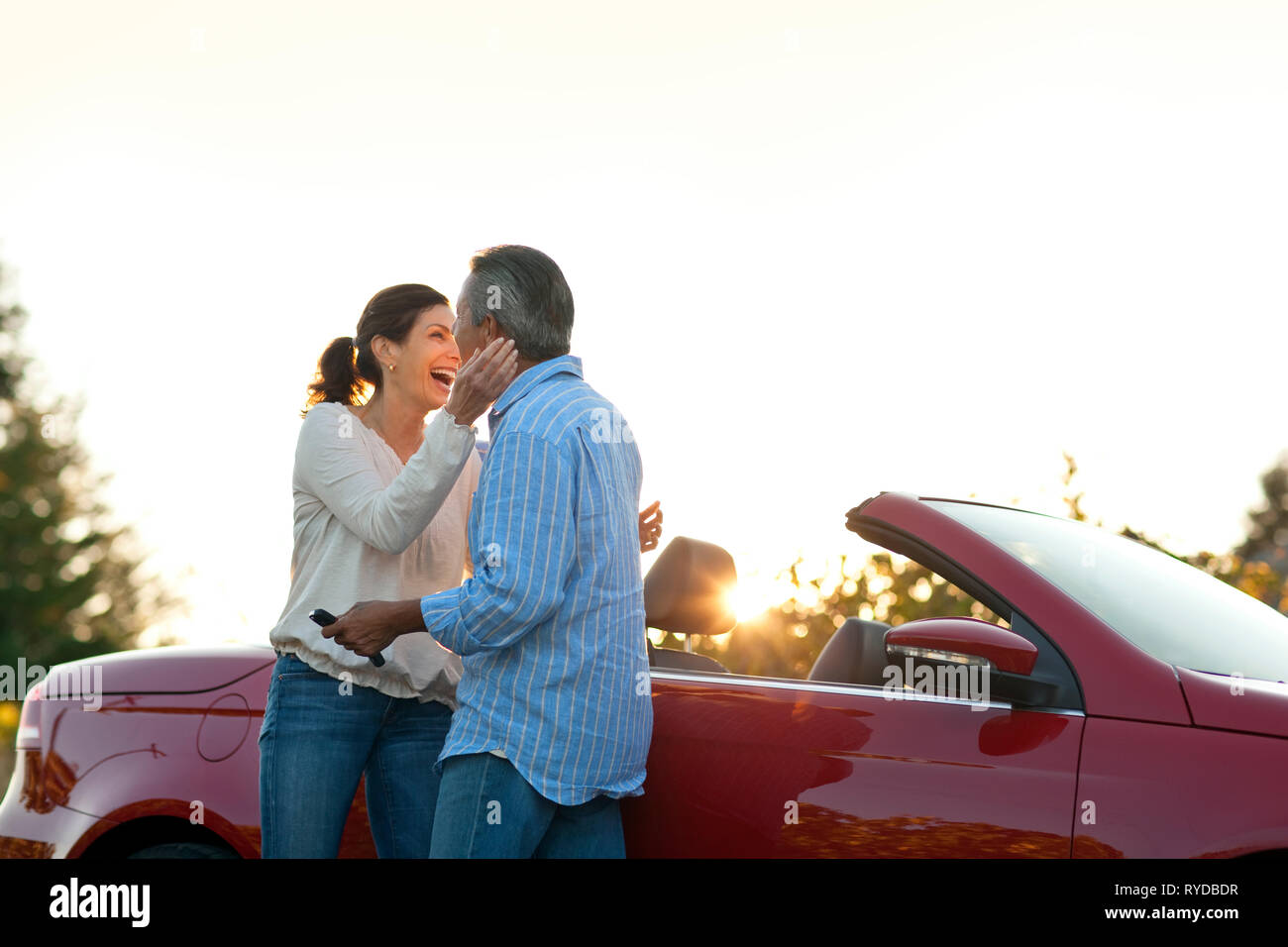 Mature couple hugging next to their car. Stock Photo