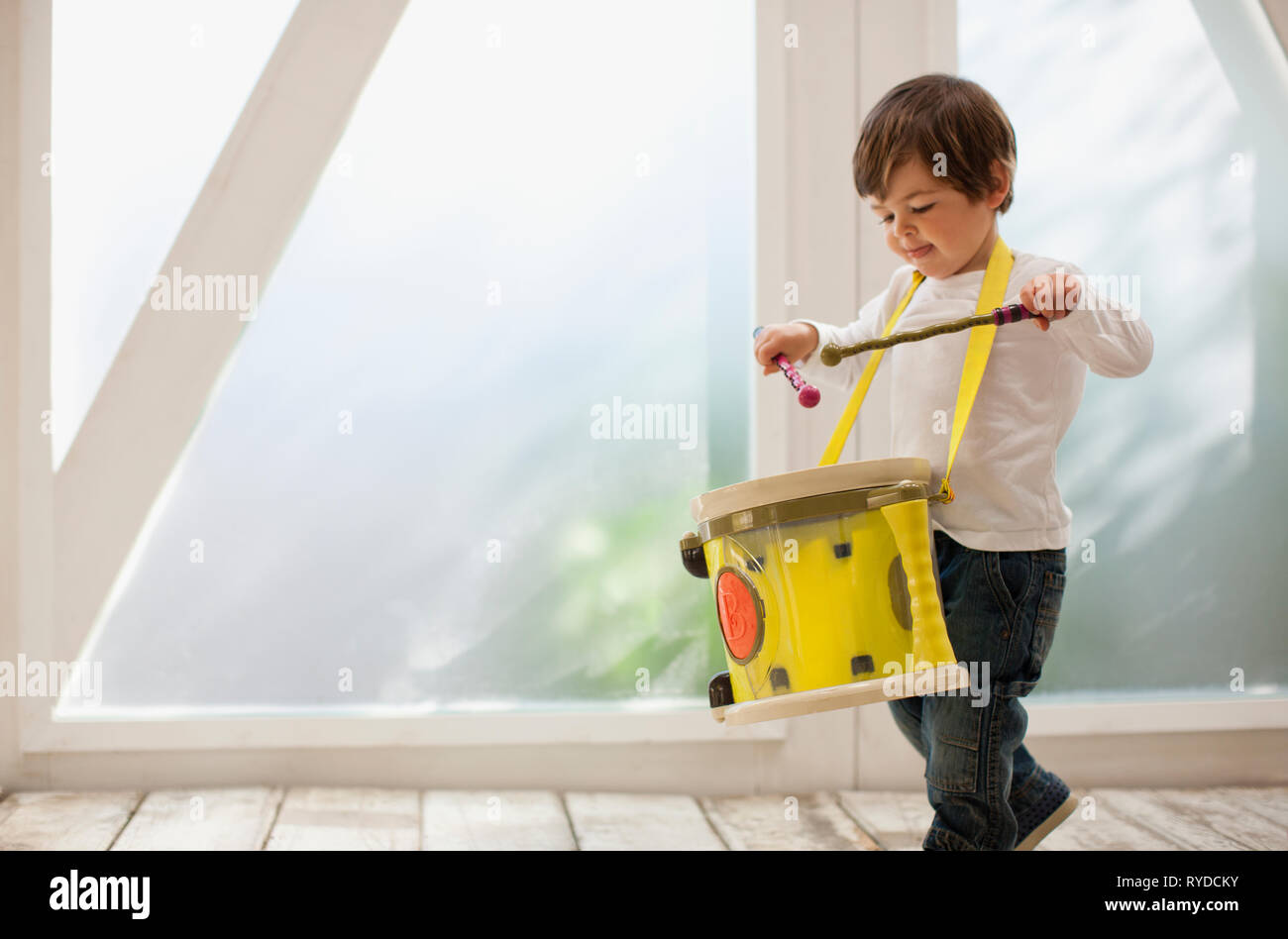 Toddler boy playing with his toy drum. Stock Photo