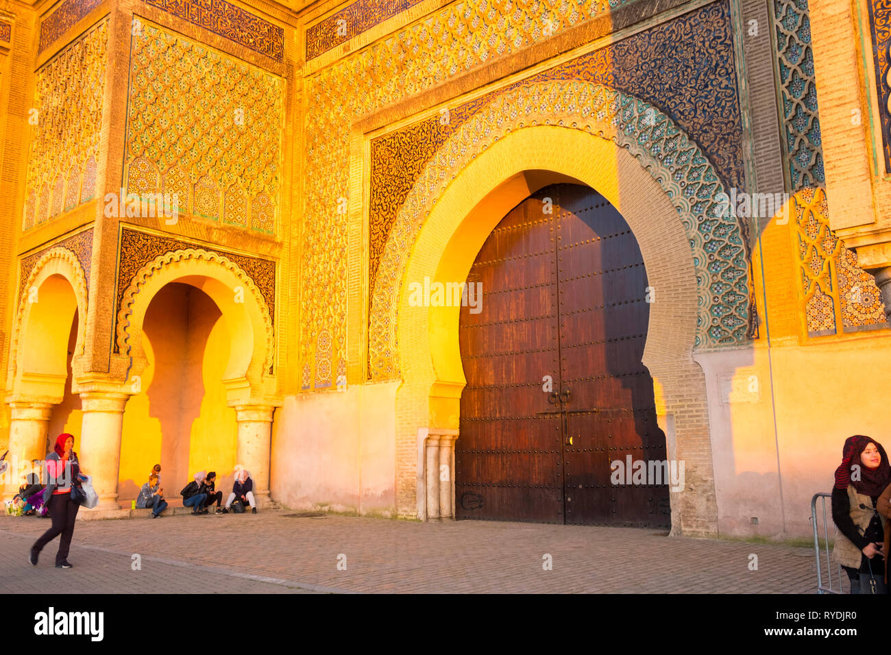 Meknes, Morocco - April 4, 2018: Moroccans in front of Bab Al-Mansour historic gate during golden hour late afternoon. Horizontal Stock Photo