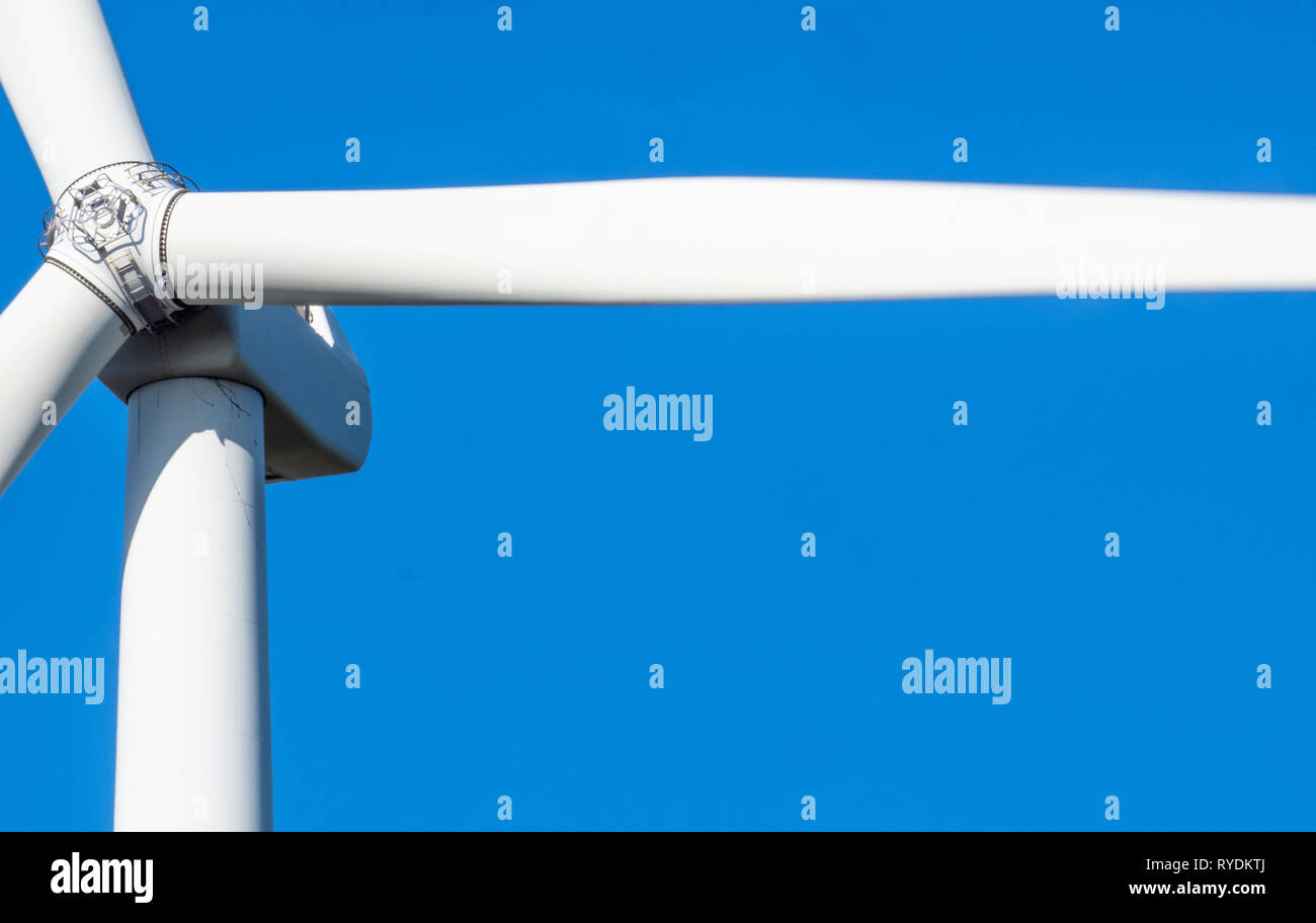 Detail of a large horizontal axis wind turbine in motion with tower rotor blades and nacelle which houses the electricity generator - South Wales UK Stock Photo