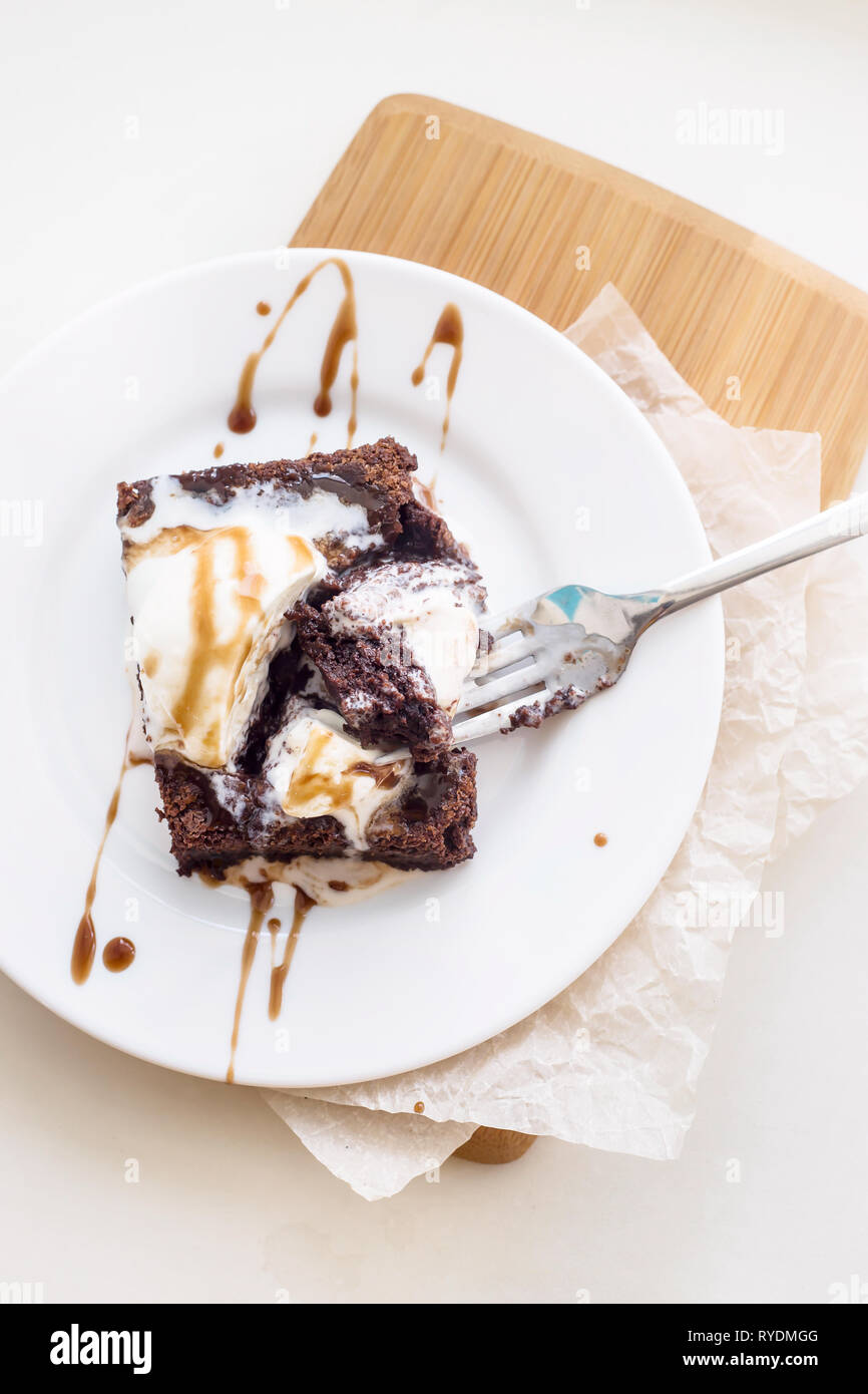 Chocolate Brownie with a scoop of vanilla ice cream mod chocolate sauce on a white plate. Top view, flat lay Stock Photo