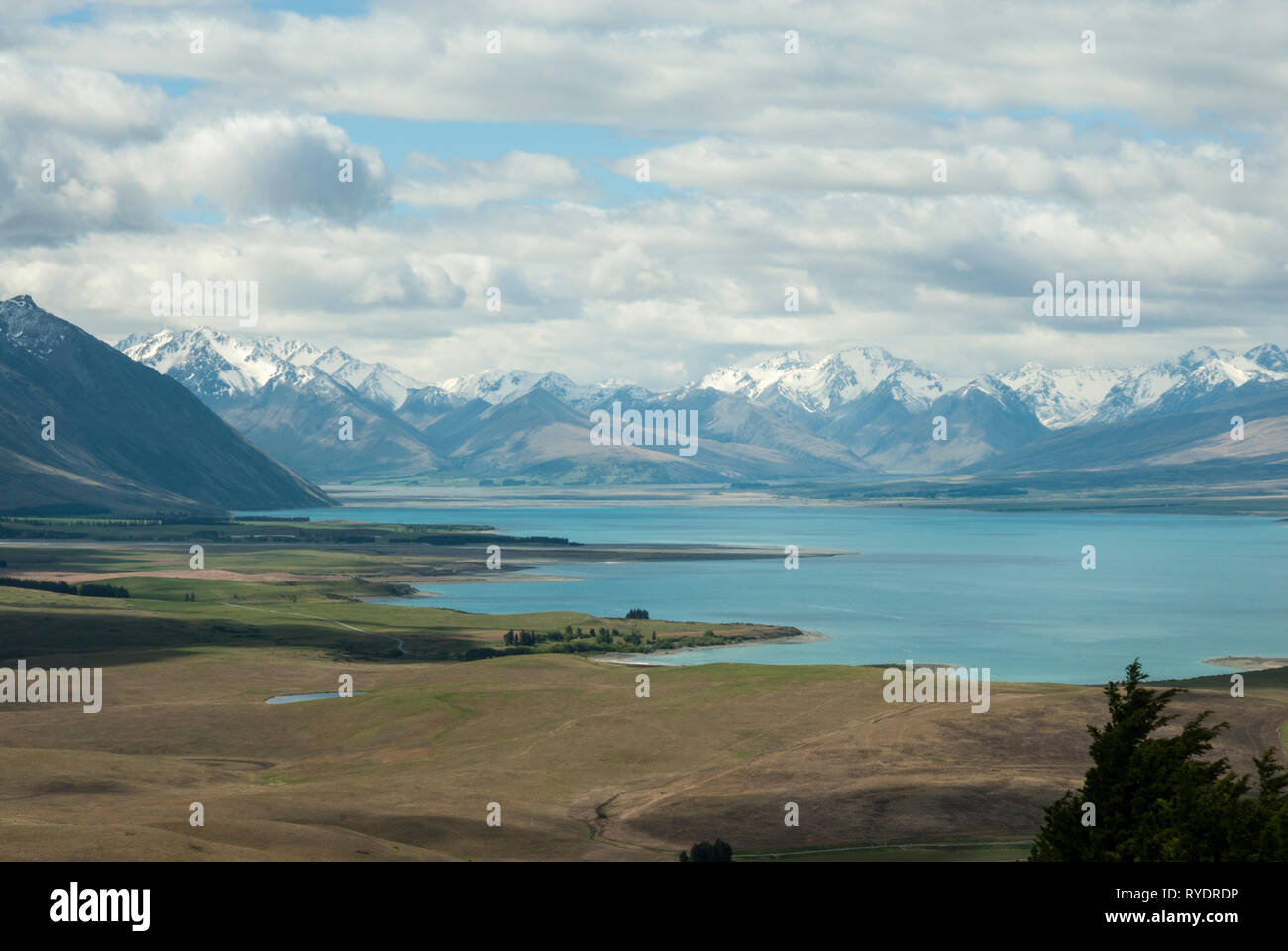 Sunning pale blue Lake Tekapo, NZ with snow capped Southern Alps in the background on a sunny day in spring. Stock Photo