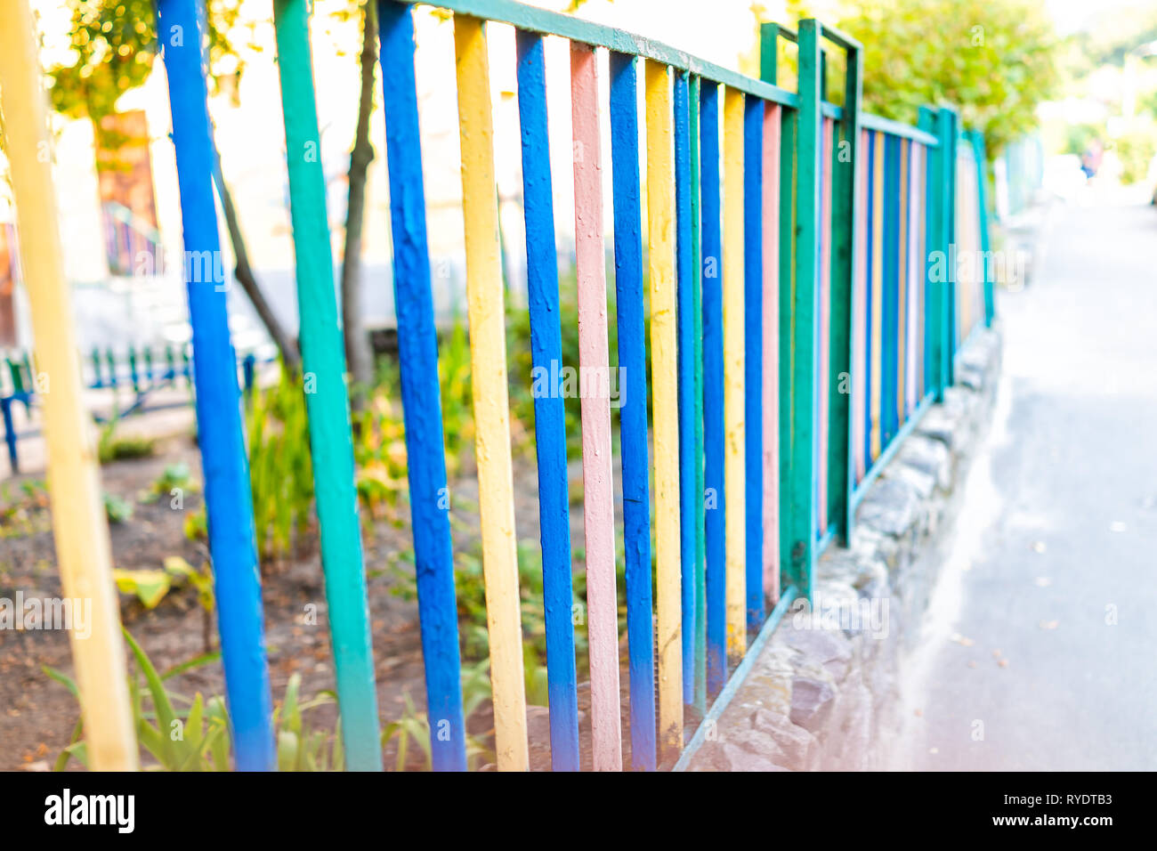 Multicolored rainbow colored blue pink green and yellow bar railing fence on sidewalk in urban city with vibrant colors Stock Photo