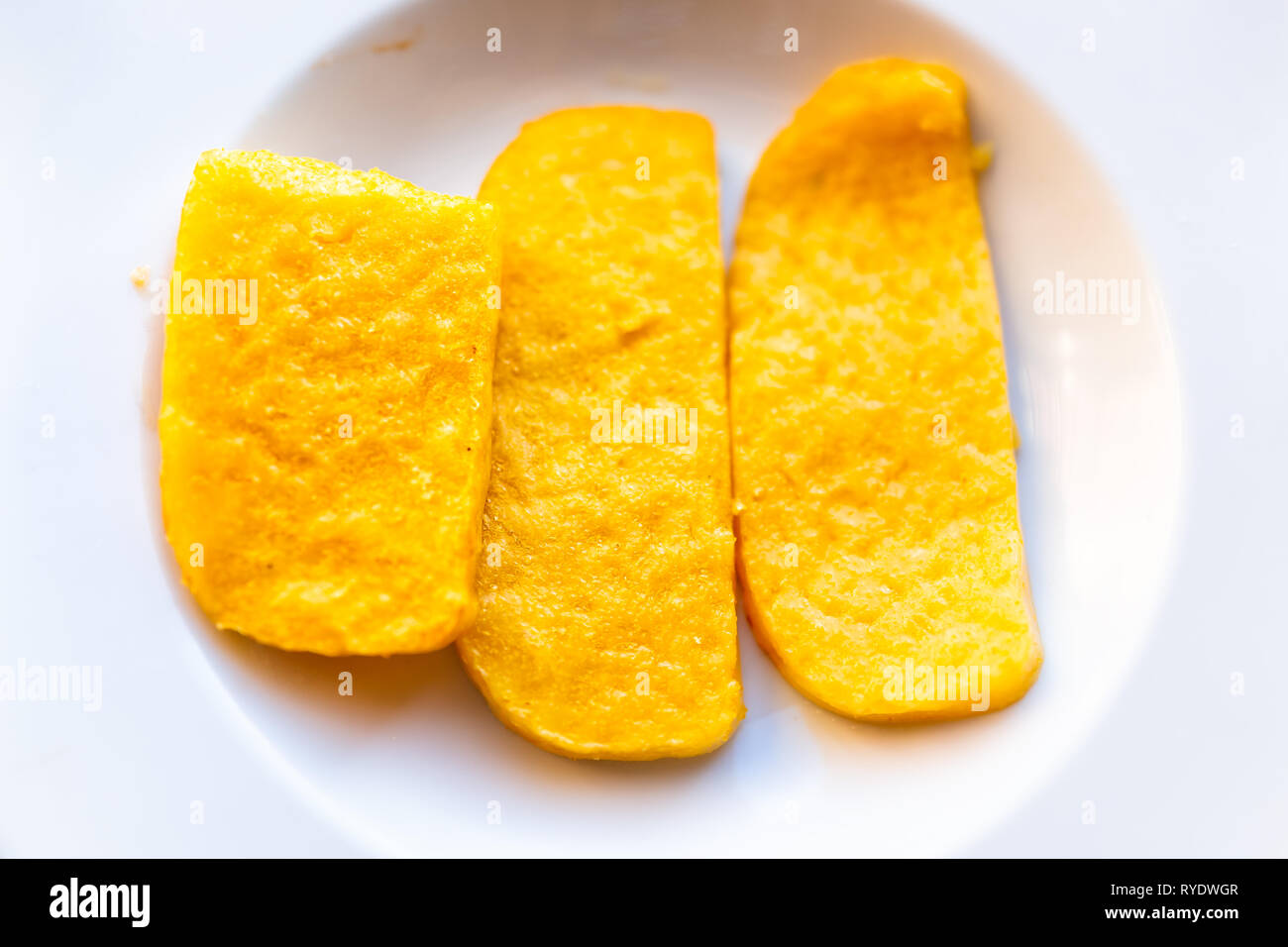 Polenta yellow orange corn cakes fried flat top view above down on white plate in restaurant appetizer golden color Stock Photo