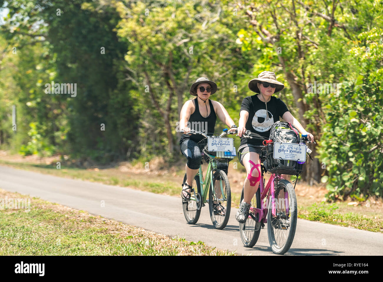 Sanibel Island, USA - April 29, 2018: People riding bikes bicycles on trail sidewalk in park by beach and road in Captiva Fort Myers, Florida Stock Photo