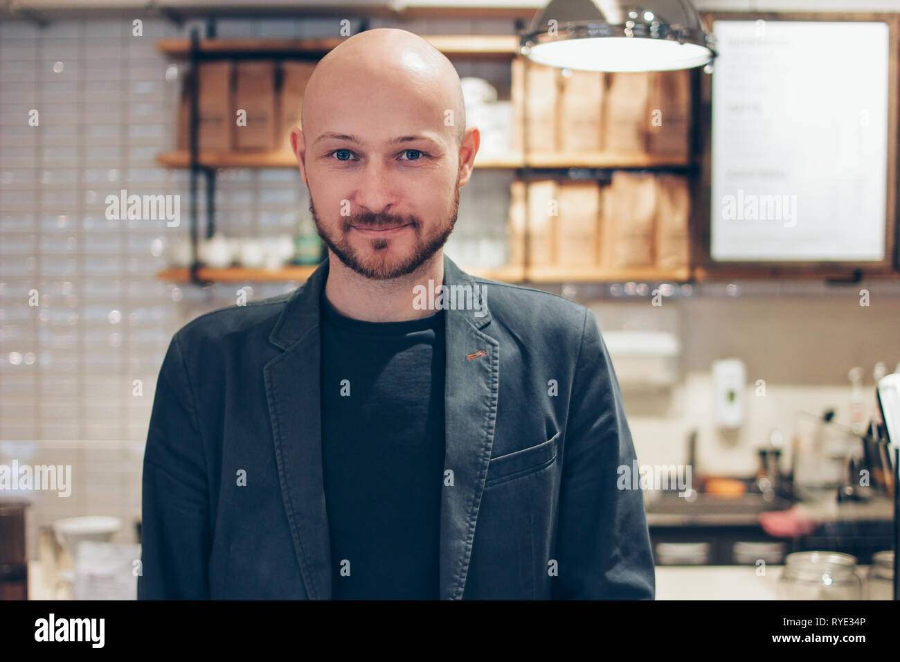Bald Man Sitting With Dog While Using Laptop At Cafe Stock Photo