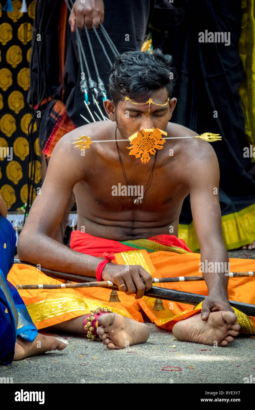 Man resting on ground, being pulled by ropes and hooks pierced in his back - Thaipusam festival - Singapore Stock Photo