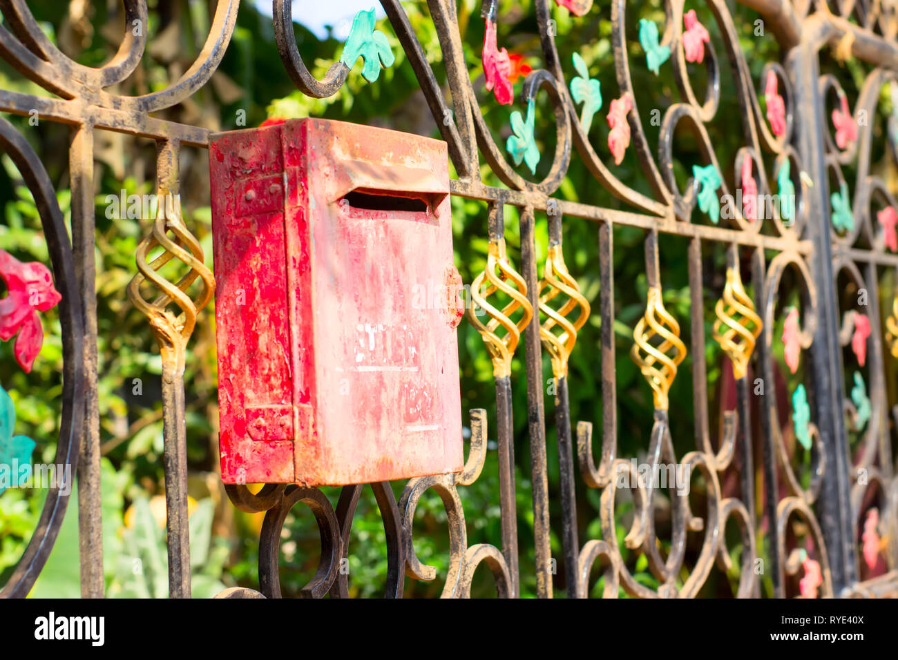 Red metal mailbox on a beautiful iron fence decorated with patterns Stock Photo