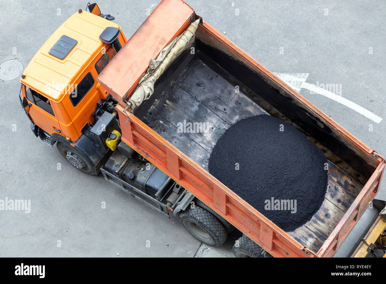 Heavy industrial dump truck unloading hot asphalt .City road