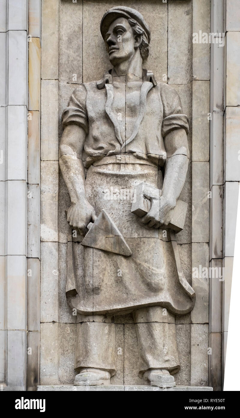 Bas relief of a symbolic bricklayer with brick and trowel in the Socialist Realist artistic style near the Constitution Square of Warsaw, Poland. Stock Photo