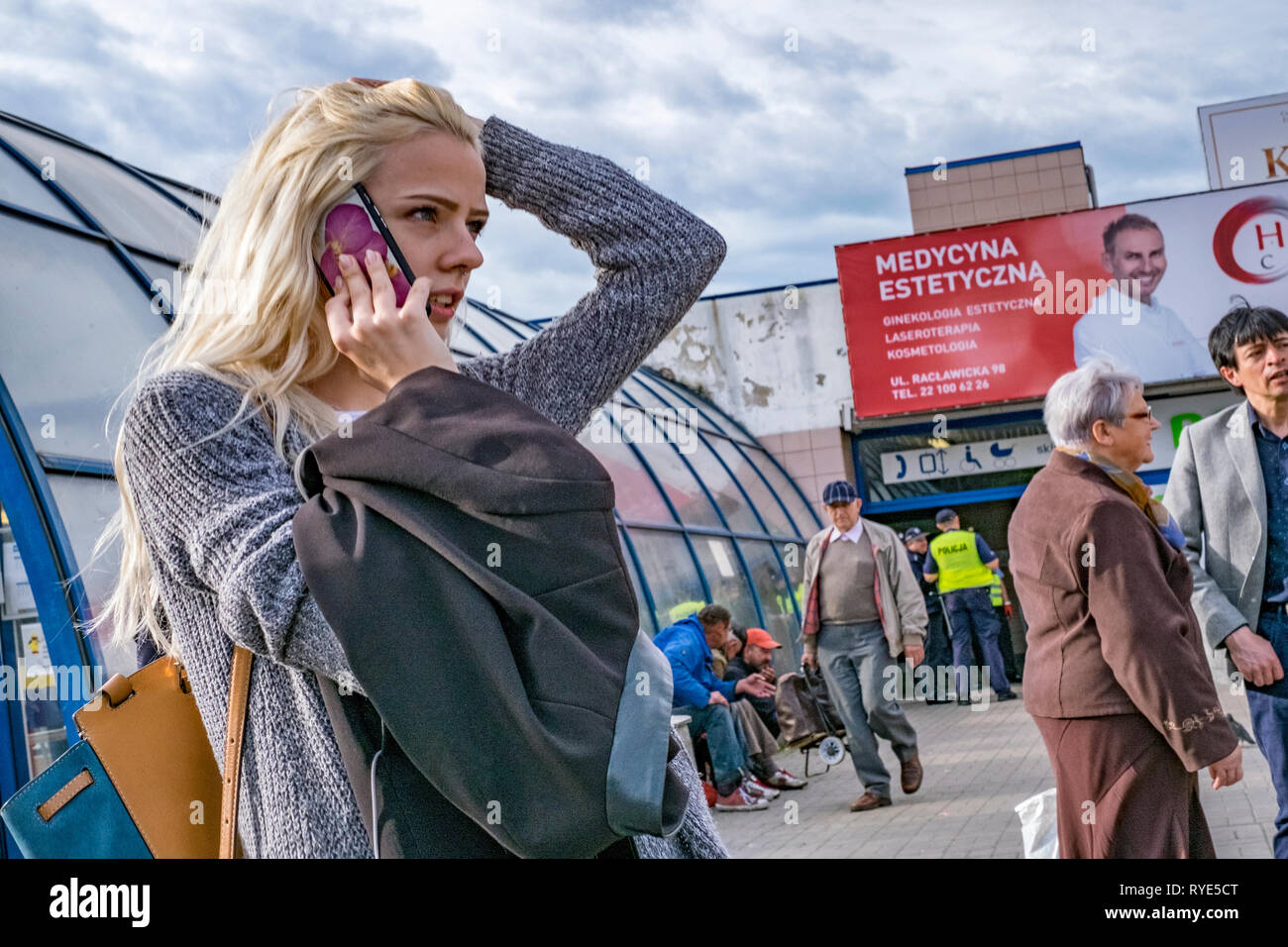 Young girl on mobile phone with arm raised over her head while talking in Warsaw, Poland Stock Photo