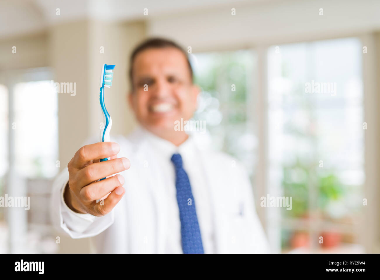 Middle age dentist man holding toothbrush and smiling Stock Photo