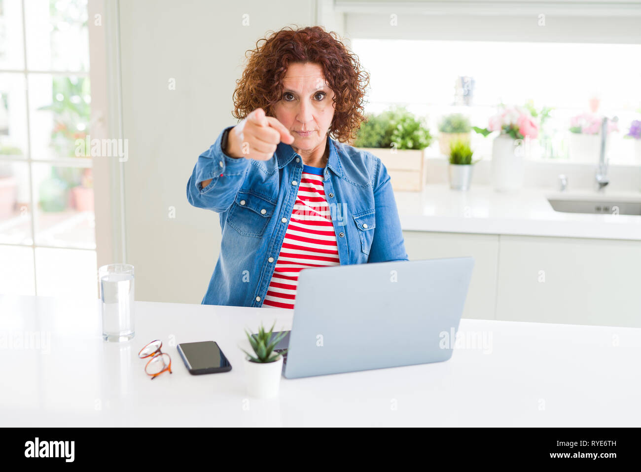 Senior woman working using computer laptop pointing with finger to the ...
