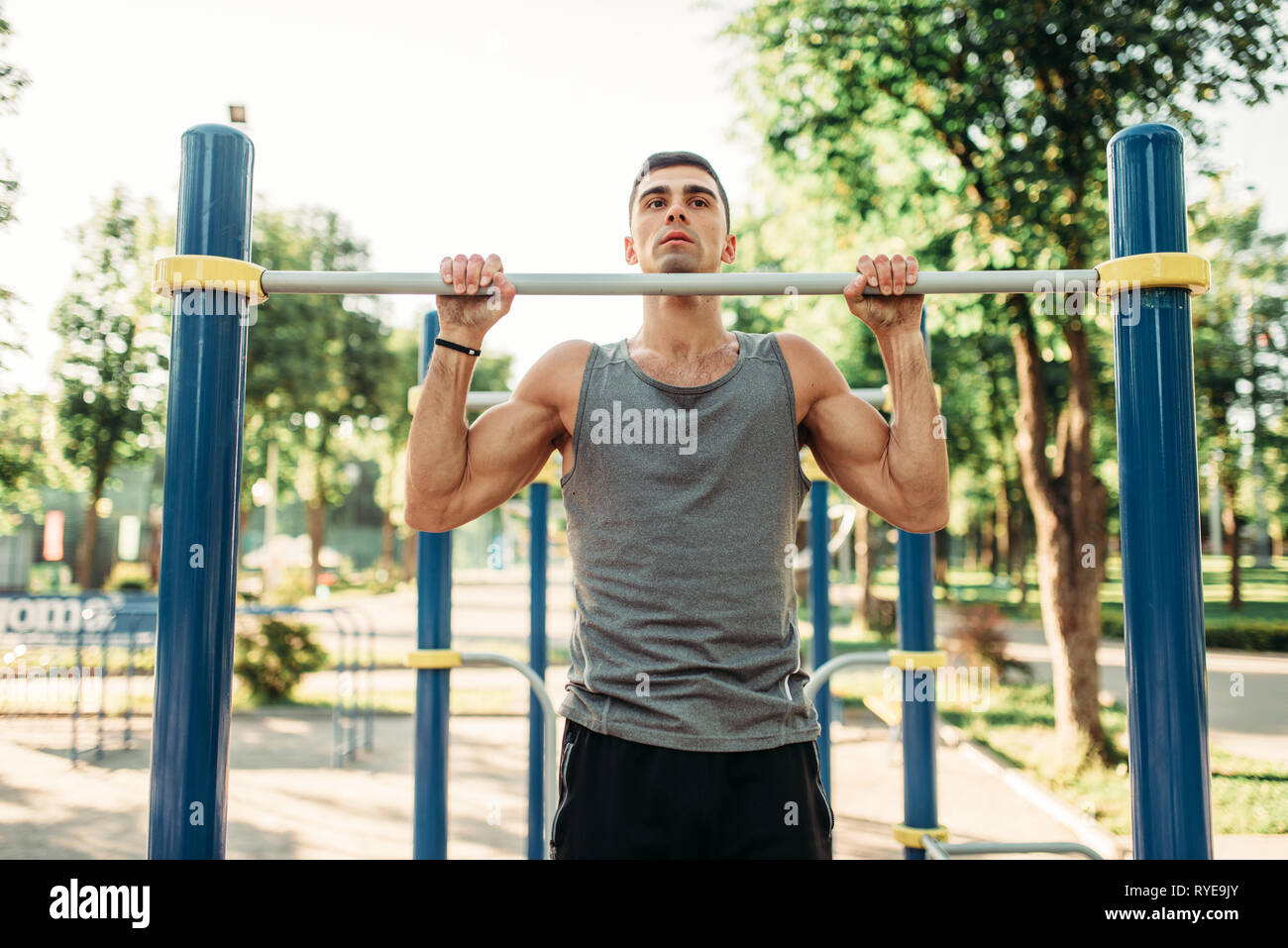 Athlete doing exercise on horizontal bar outdoor Stock Photo - Alamy