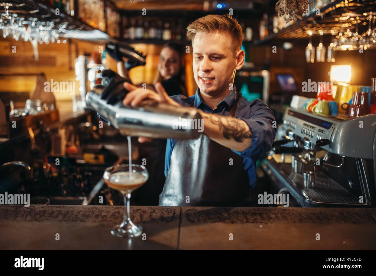 Male barman pouring the drink from the shaker Stock Photo