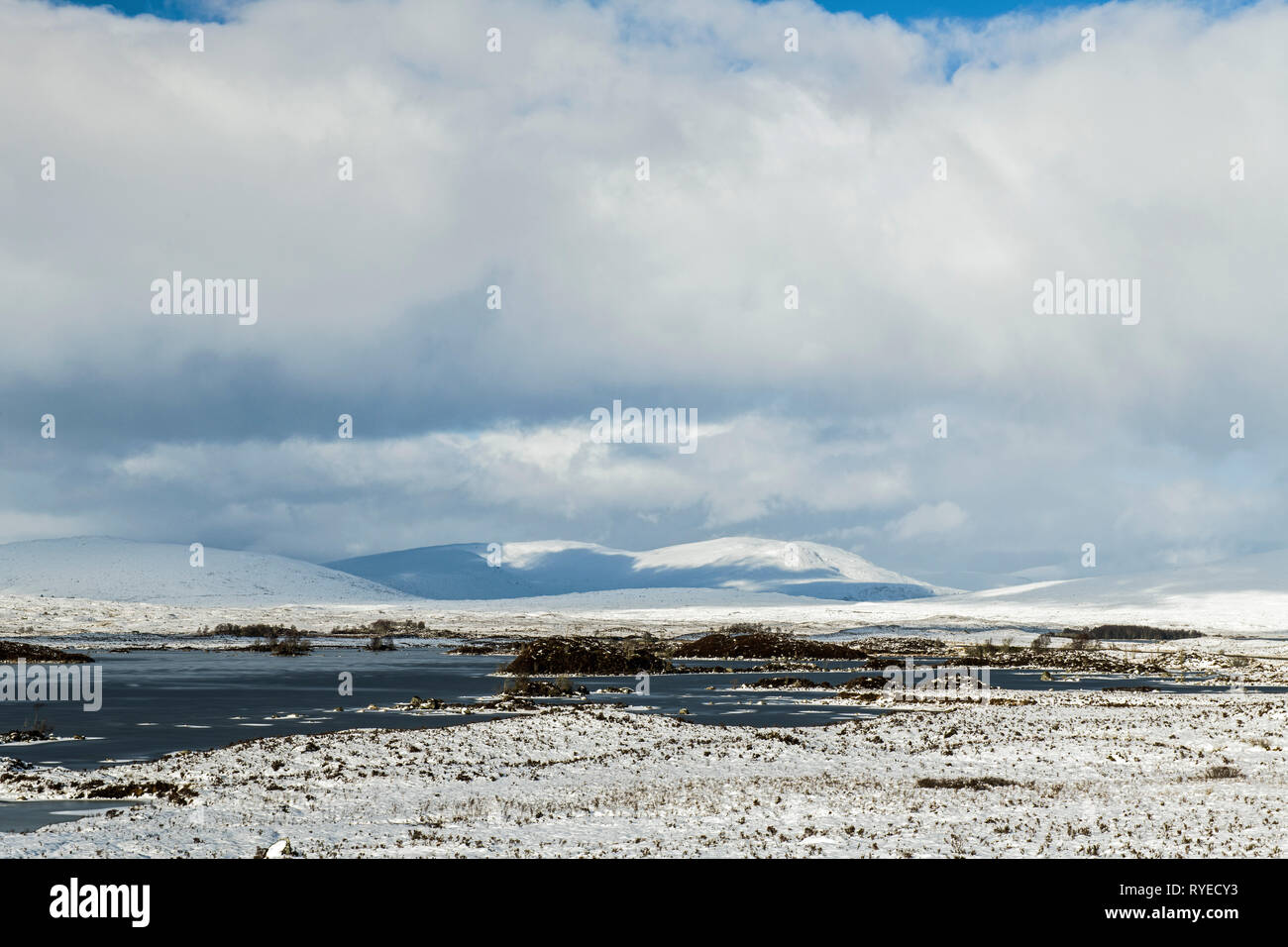 Rannoch Moor in the Scottish Highlands under snow in February. The photo shows snow covered mountains with cloud shadows on them. Stock Photo