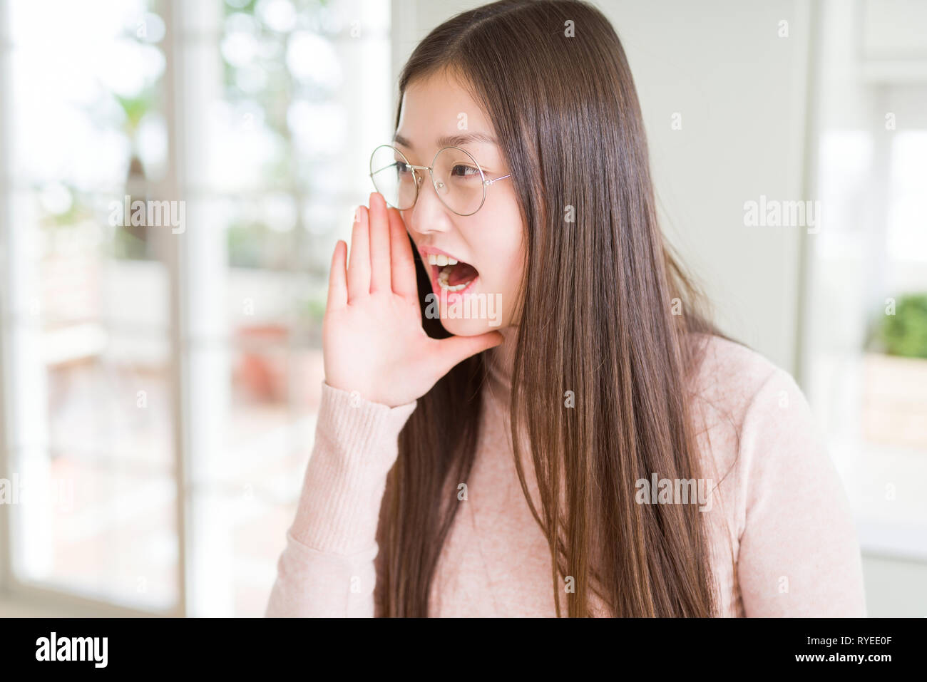 Beautiful Asian woman wearing glasses shouting and screaming loud to ...