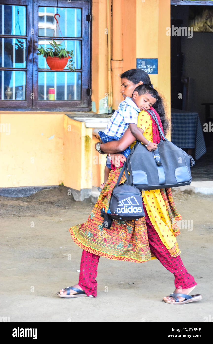 Sri Lankan mother carries sleeping child and adidas bag on railway