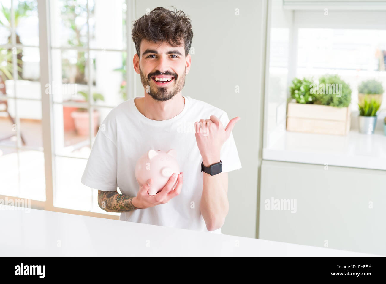 Young man holding piggy bank as insurance investment pointing and ...