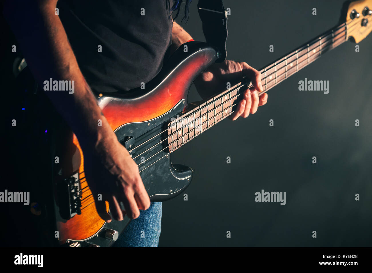 Guitarist plays on of bass guitar on a dark stage, soft selective focus, live music theme Stock Photo
