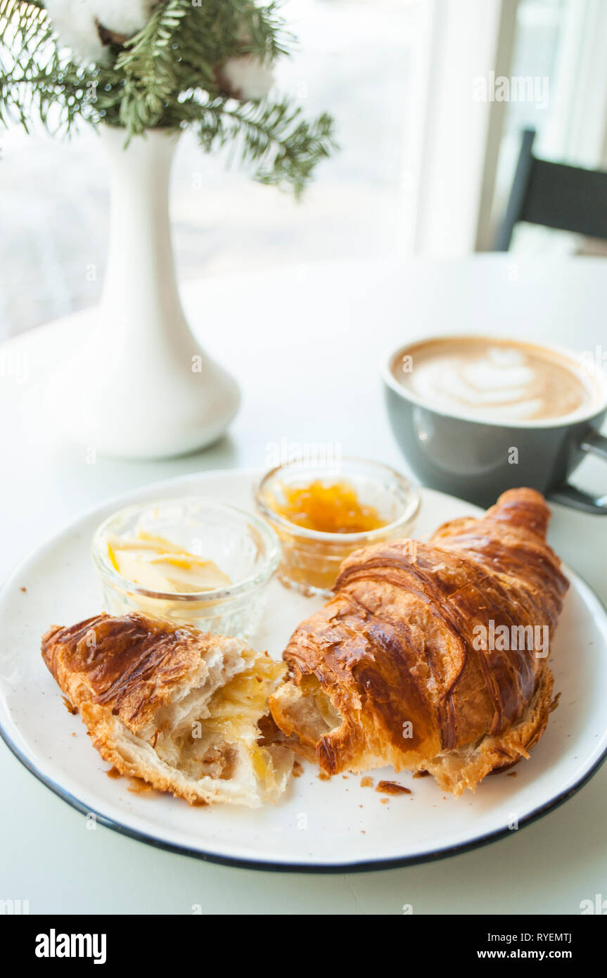 Fresh croissant with jam and butter and cappuccino with beautiful latte