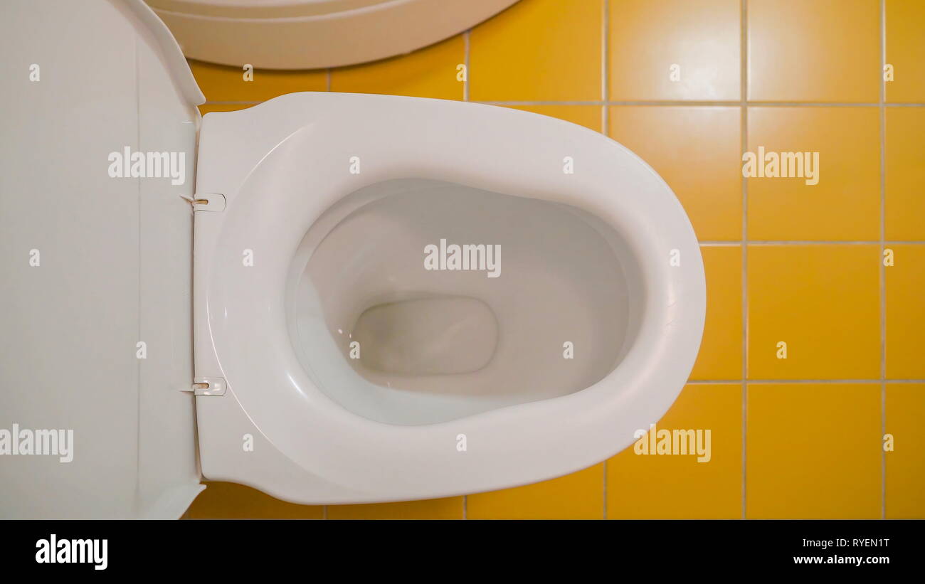 The water flushing inside the toilet bowl in the bathroom and the tiled