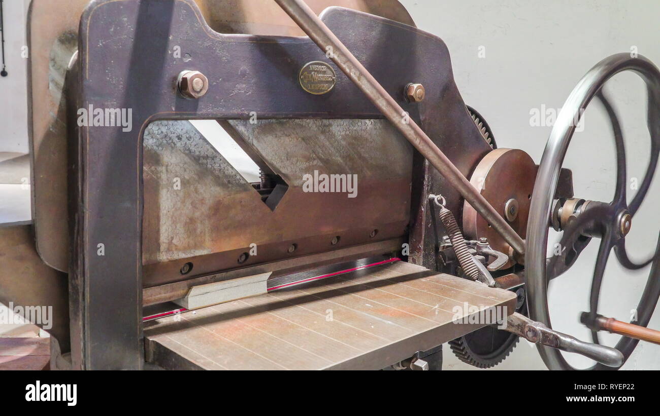 A vintage old style paper cutter inside the printing station with the spinning wheel on the side making it to run Stock Photo