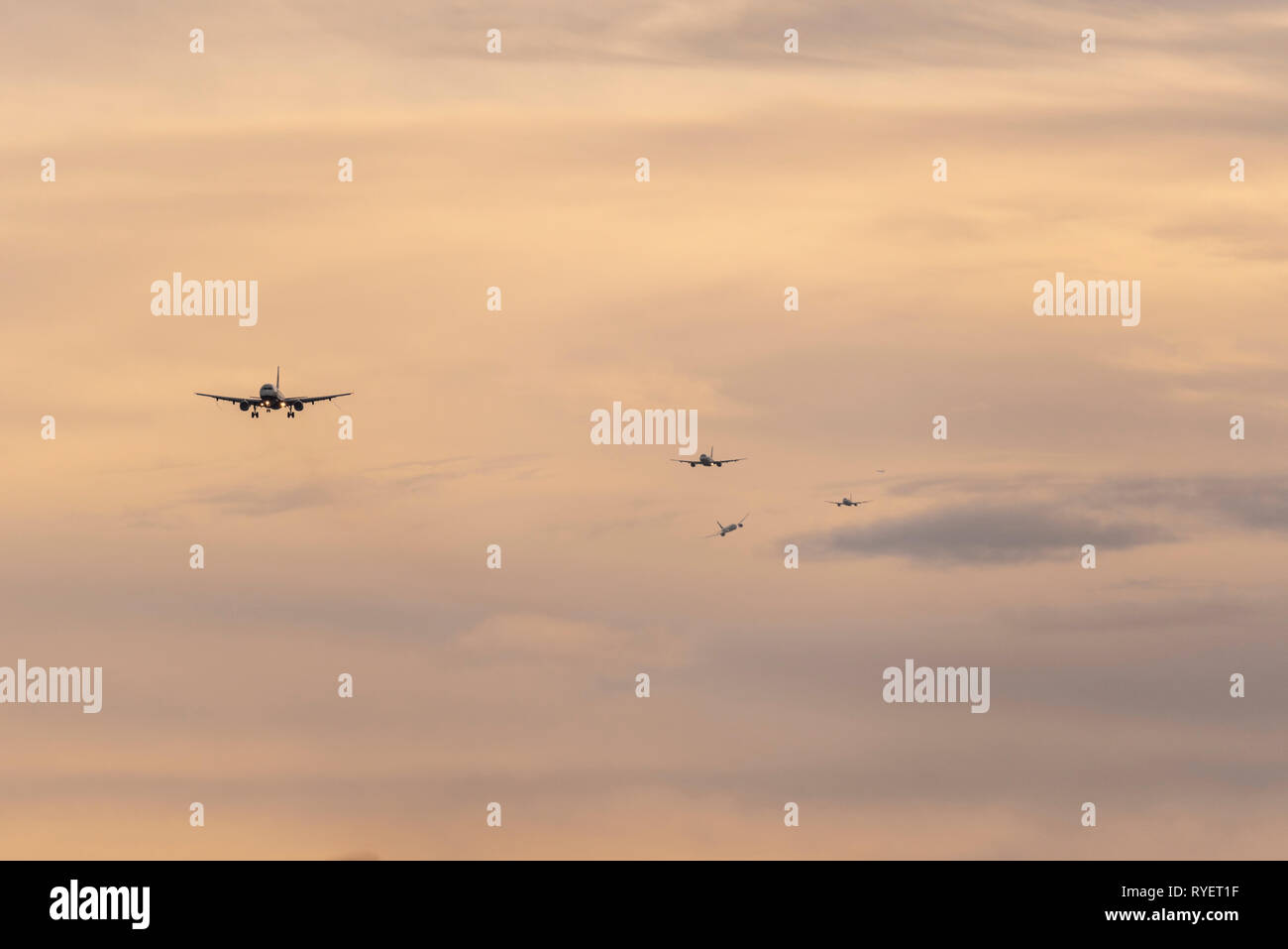 Queue of planes on final approach to land at London Heathrow Airport, London, UK at dawn. Landing airliners. Busy finals for landing at airport Stock Photo