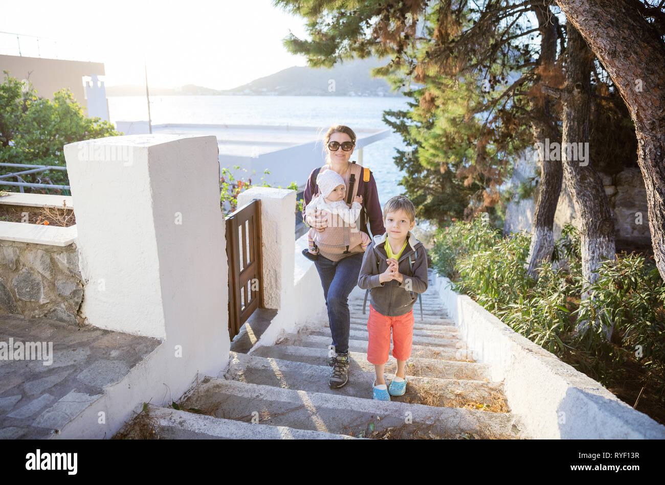 Caucasian young woman with baby daughter and preschool son walking up stairs in seaside town Stock Photo