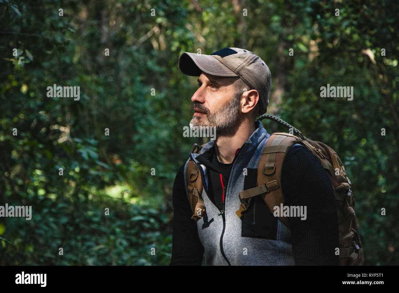 Closeup of a hiker in a wild green forest looking up to sunlight, concept nature Stock Photo