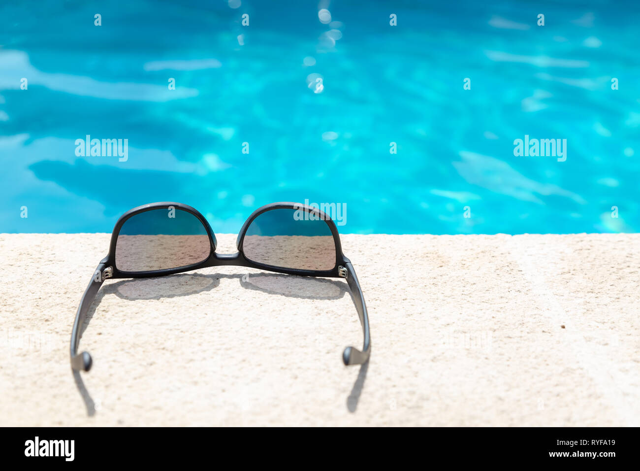 Sunglasses near the edge of a swimming pool Stock Photo