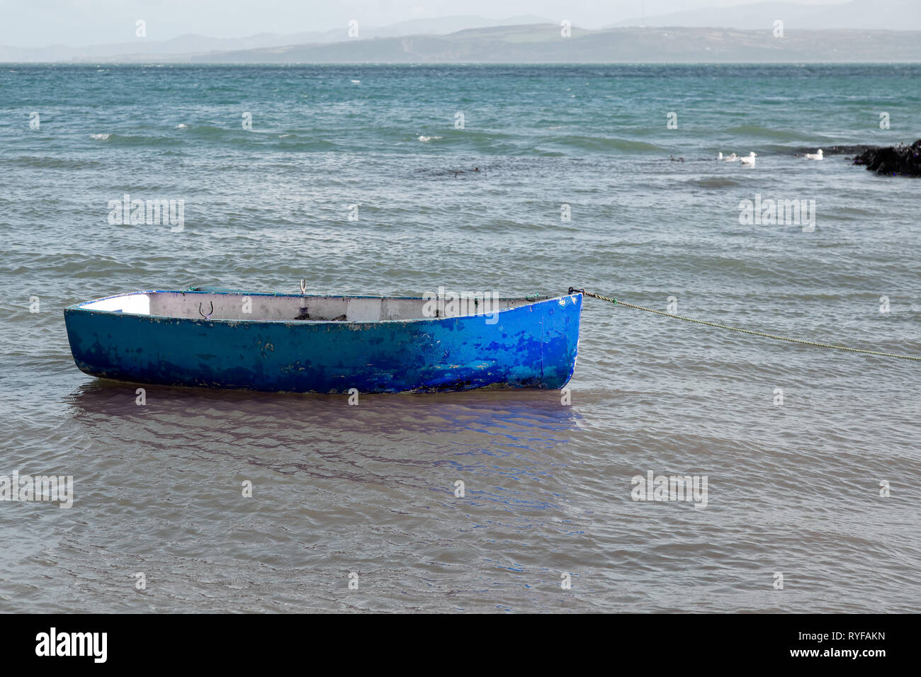 Small blue rowing boat moored in the sea Stock Photo