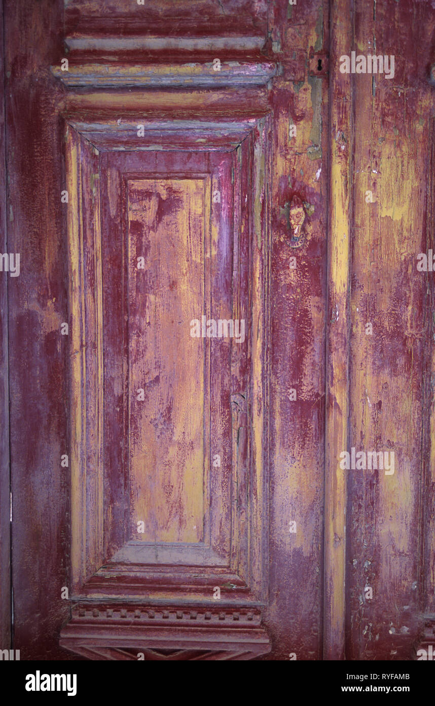 close-up of a weatherbeaten doorpanel in shades of pink, maroon and yellow Stock Photo