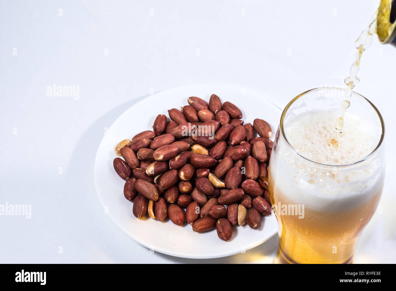 Beer is poured into a glass and peanuts in the saucer. Stock Photo