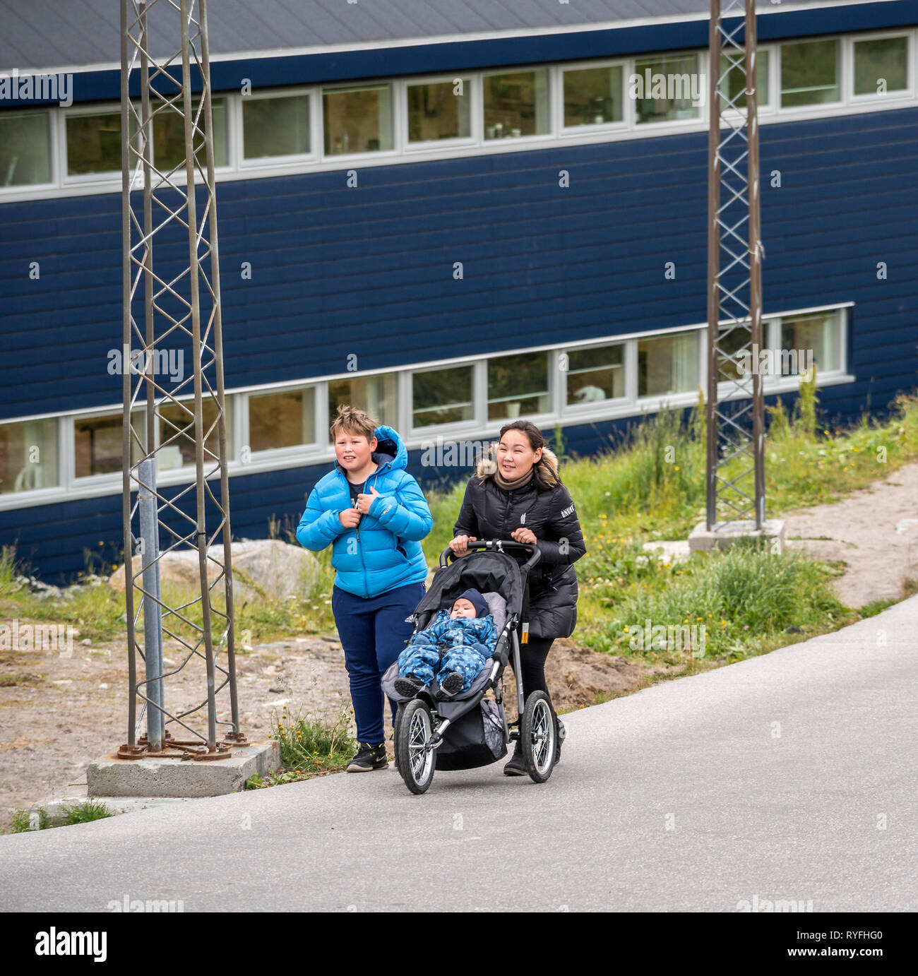 Teenage girl pushing a baby stroller with her friend, Qaqortoq, South Greenland Stock Photo