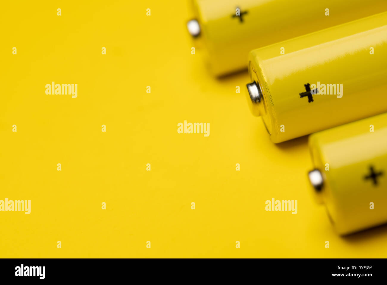 Close up shot of yellow AAA alkaline or rechargeable NiMH batteries or on yellow background, shallow focus Stock Photo