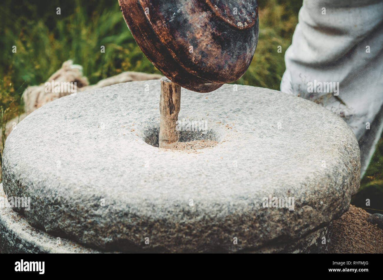 The ancient quern stone hand mill with grain. The man pouring grain
