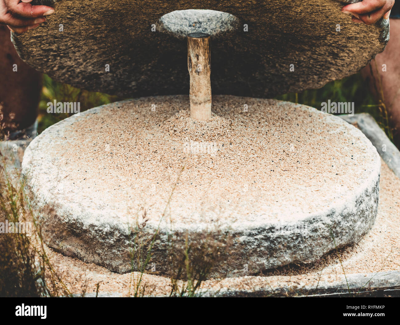 The ancient quern stone hand mill with grain. The man raises the top