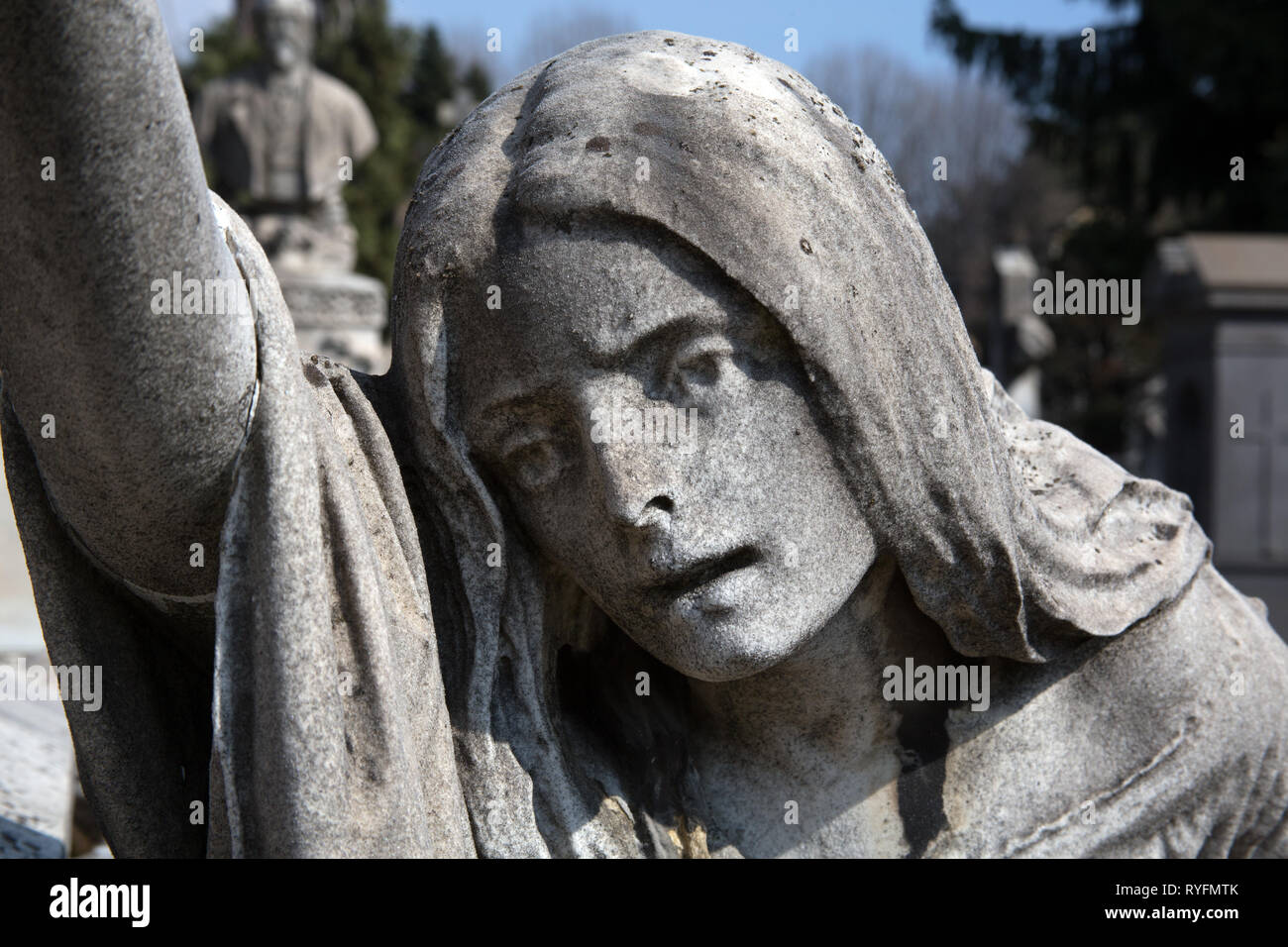 Statue / monument of a young woman reaching out grave stones in the Cimitero Monumentale di Milano - Monumental Cemetery - Milan Italy Stock Photo