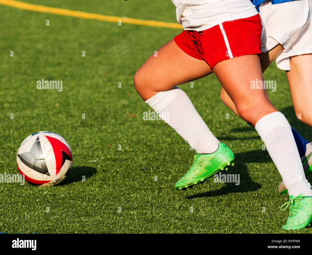 Two girls chasing a soccer ball during a high school game on a sunny afternoon. Stock Photo