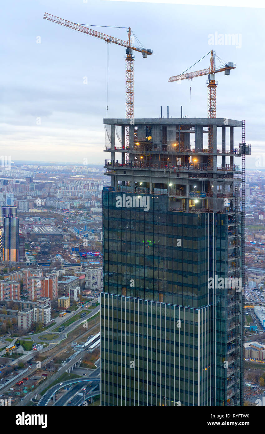 the construction of a modern skyscraper. Tower crane at construction site in evening sunlight