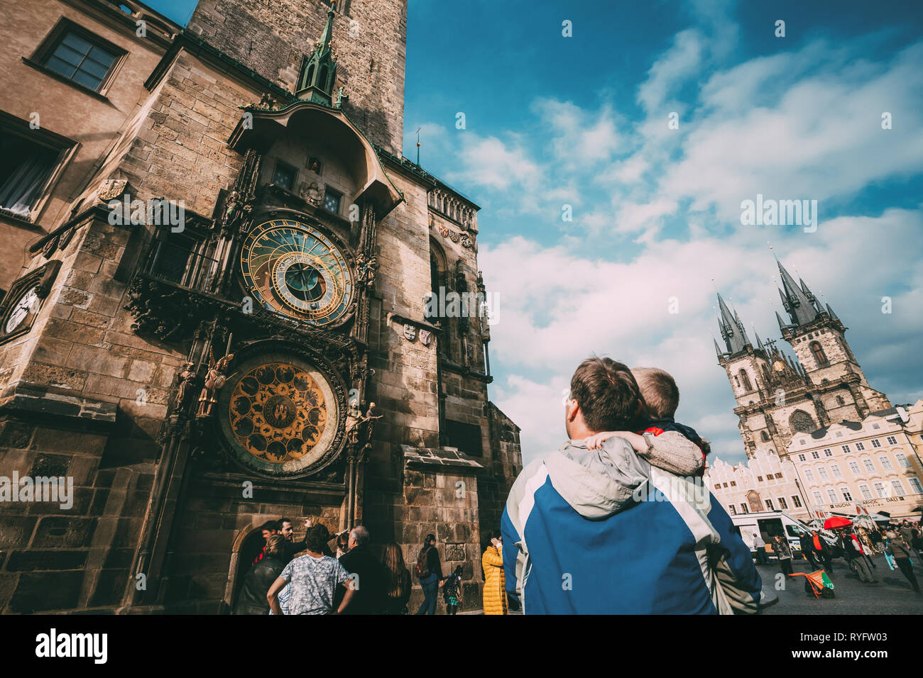 PRAGUE, CZECH REPUBLIC - OCTOBER 9, 2014: The unrecognizable man and boy are looking at astronomical clock in Prague. Tower of town hall with astronom Stock Photo
