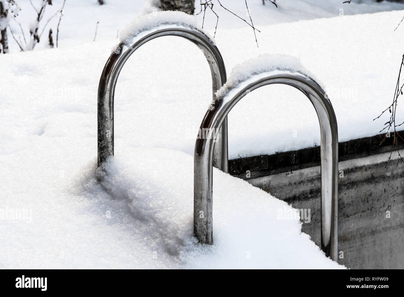 metal staircase in the outdoor pool covered by snow Stock Photo