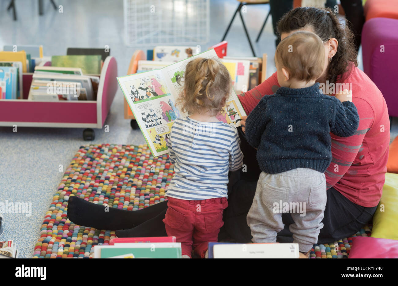 Mother reading a book to her children in a library Stock Photo