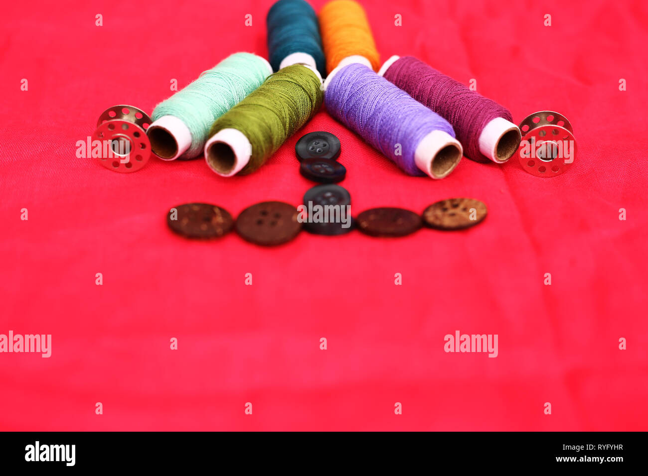 Picture of sewing thread, bobbin and button. Isolated on the red ...