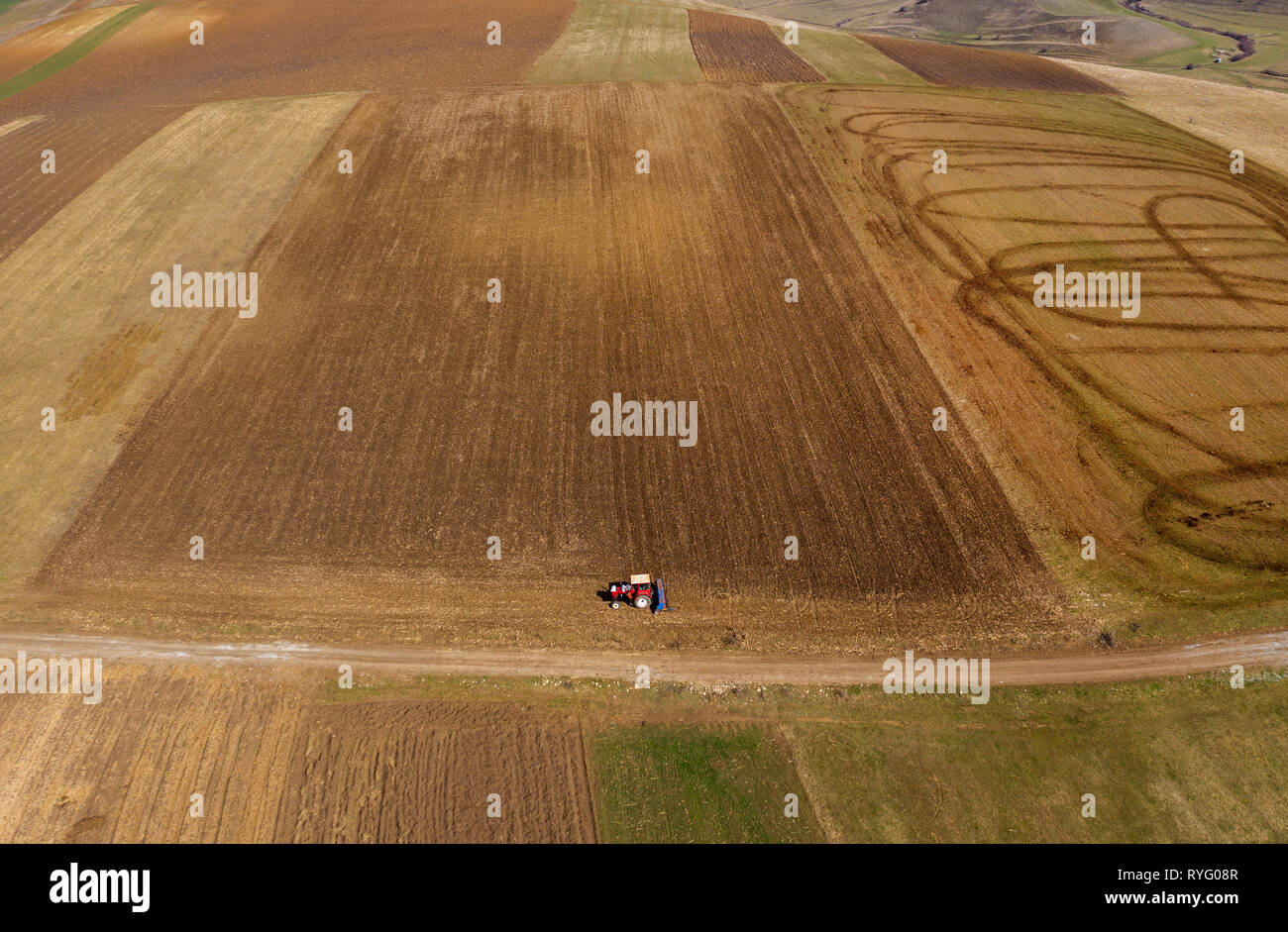 Aerial top view of a tractor, combine harvester plowing agricultural ...