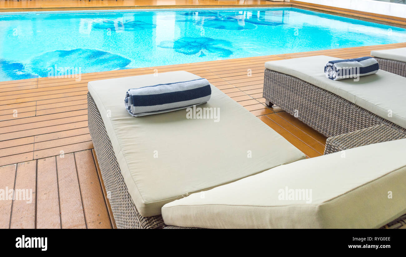 Daybed sun lounger chair poolside with towel and pool looking inviting