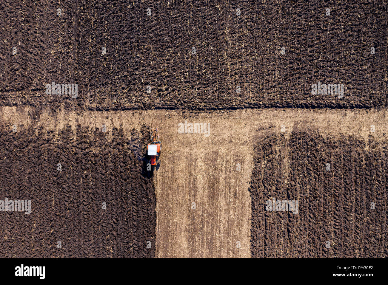Aerial top view of a tractor, combine harvester plowing agricultural ...