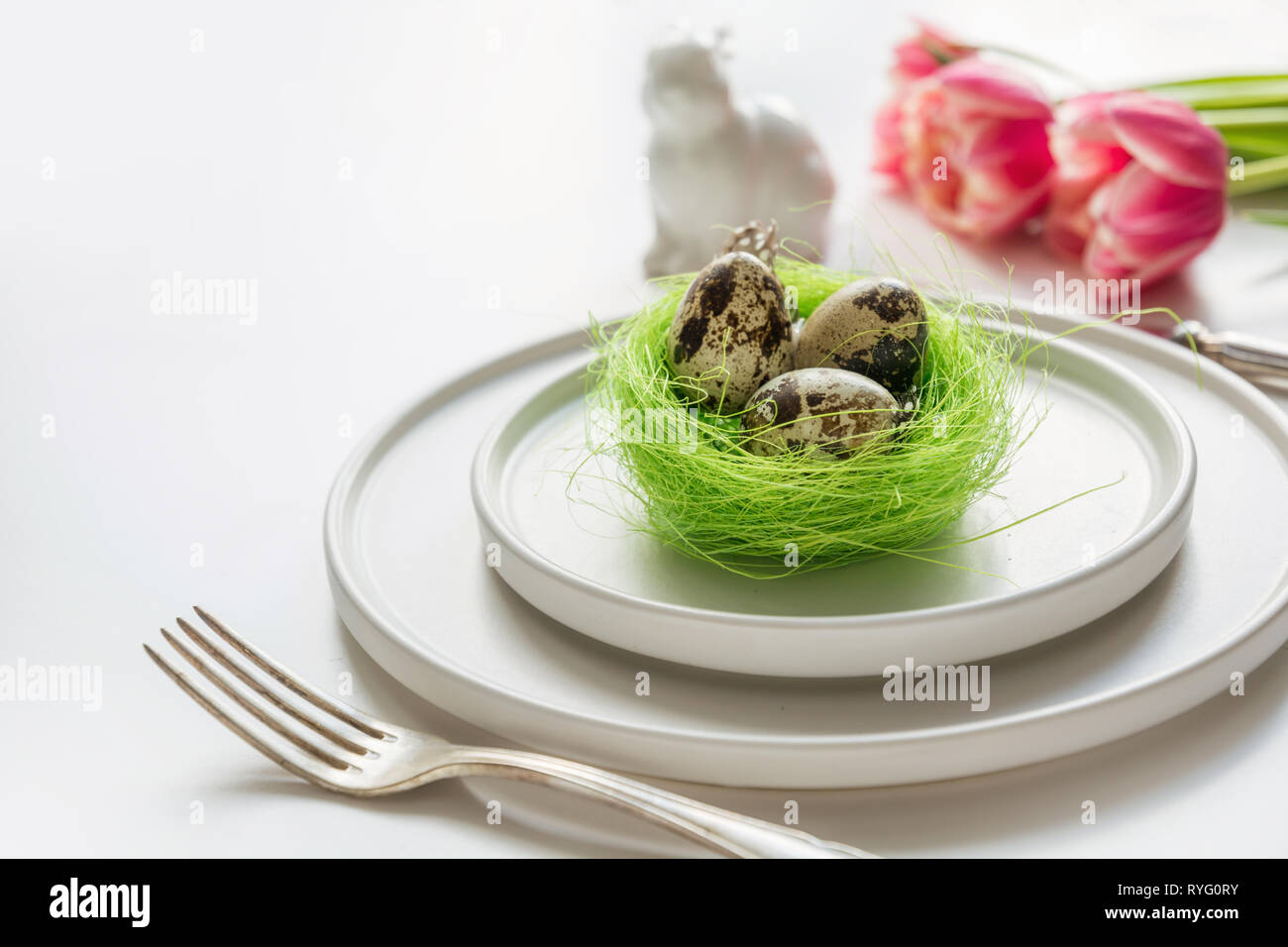 Easter table setting with pink tulip on white. Spring romantic dinner. Space for your text. Stock Photo